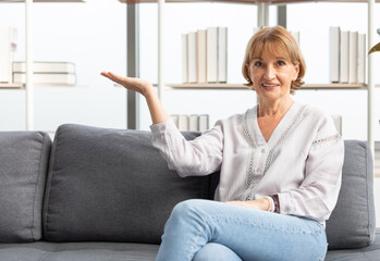 portrait senior woman smiling and raise arm showing pose on sofa