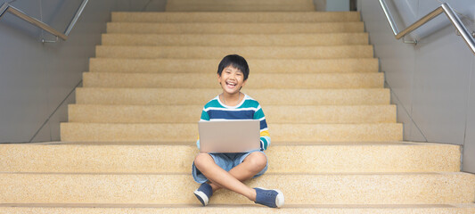 Portrait of Cute Asian boy studying or playing game with laptop computer - 476835108
