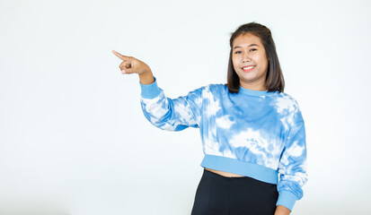 Portrait Asian beautiful woman wearing casual shirt standing poses, pointing advertisement on white background, blank copy space with an isolated smiling look at the camera.