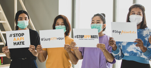 Group of multi races Asian women wearing protective hygiene face masks shake banners during participants in Asian American Pacific Islanders rally marching protest to stop hate on AAPI citizen.