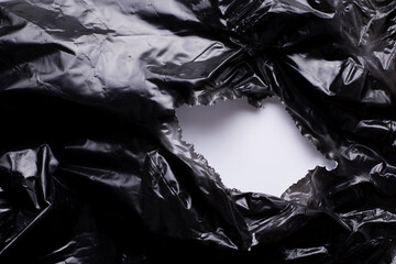 Torn, damaged black plastic foil, whole in a black plastic film