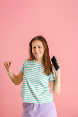 Fototapeta premium Smiling brunette dancing listening to music with headphones. Girl with wired headphones