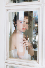 Beautiful curly-haired bride in a luxury wedding dress in a restaurant with wedding decor