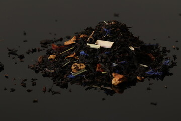 Long leaf black tea with raspberries, apple and fruit aroma. Black tea on a black background. 