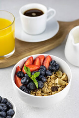 Continental breakfast with granola, berries, coffee and orange juice on white background
