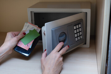 Woman hands opening metal safe in hotel room