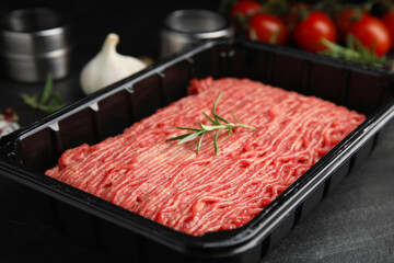 Plastic container with fresh minced meat on black table, closeup