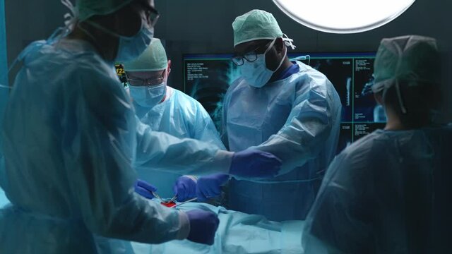 Team of professional medical surgeons performs the surgical operation in a modern hospital. Doctors are working to save the patient. Medicine, health, cardiology and transplantation concept.