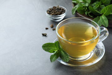 Cup of hot aromatic mint tea on grey table. Space for text