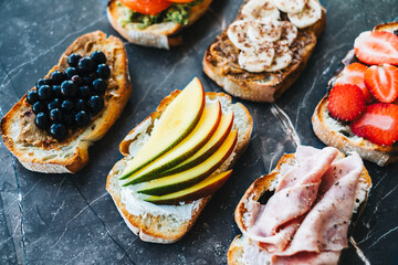 Delicious healthy toasts mix for breakfast, lunch or snack, dark marble background.
