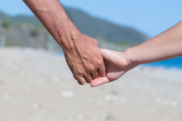 Couple hands held together on a natural sea background, close up