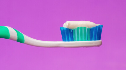 Toothbrush with toothpaste on a purple background, dental care