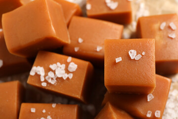 Tasty caramel candies and sea salt on table, closeup