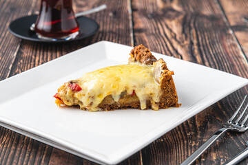 Mushroom quiche pie with tea on white plate on wooden table