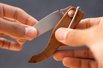 hands holding a sharp folding dagger