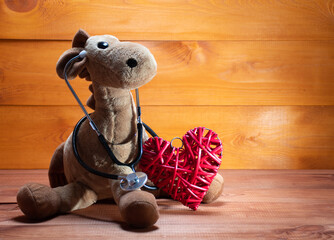 A big plush toy holds a big red heart  on a white background, medical table: pediatric cardiology,...