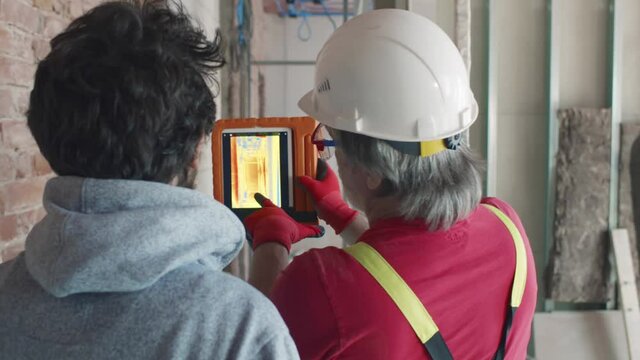 Back view of contractor and builder use infrared camera at construction site. Realtime