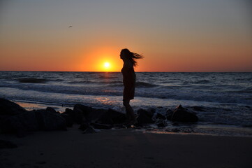 sea. the girl meets the dawn with the first rays of the sun