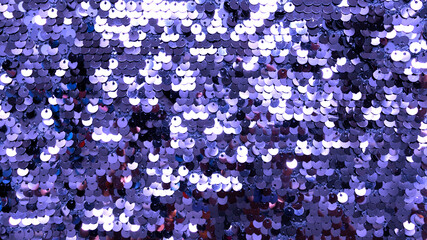 Shiny sequins on fabric in 2022 color. Color of the Year 2022 Very Peri 17-3938. Abstract shiny background, fashionable fabrics, blex, sequins. Fabric for festive events.