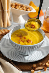 pumpkin cream soup, portion, restaurant serving, breadsticks and croutons, bright sunlight, vertical format