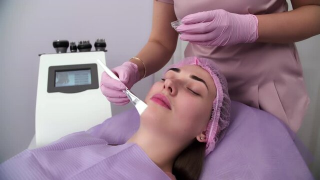 Beautiful woman receiving facial microcurrent treatment at spa salon. Beautician using electrical impulses for facial procedures. Woman in spa salon. Woman in a spa salon on cosmetic procedures.