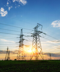 silhouette of high voltage power lines against a colorful sky at sunrise.