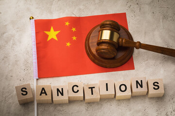 Wooden cubes with the text, the judge gavel and the flag of China, a concept on the theme of the imposed sanctions in the country