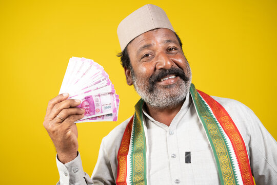 Corrupt greedy indian politician laughing by using money like a fan - concept showing of political arrogance, evil laughter and unprofessional way of money making.