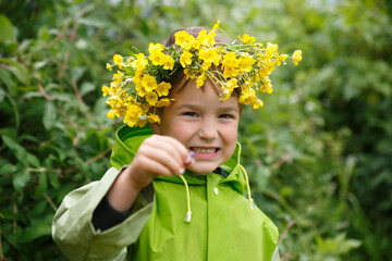 Cute little boy wearing a wreath of yellow flowers outside.