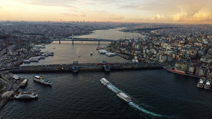 Fototapeta premium Aerial view of Galata bridge, bottom, and Halic metro bridge located in the Golden horn waterway, city of Istanbul, Turkey, during sunset.