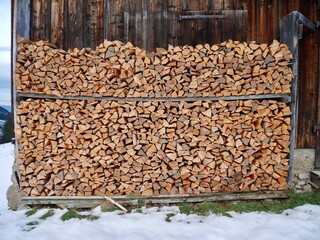 Stack of firewood in front of mountain hut in winter.