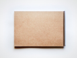 螺旋綴じの茶色いスケッチブックの裏面。茶色いコピースペース。灰色背景で真上から撮影。