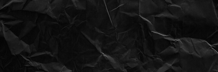 Black crumpled paper texture with folds banner. Black grunge surface. Black wallpaper background. 