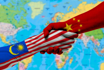 Naklejka premium Handshake between China and Malaysia flags painted on hands.With background of world map