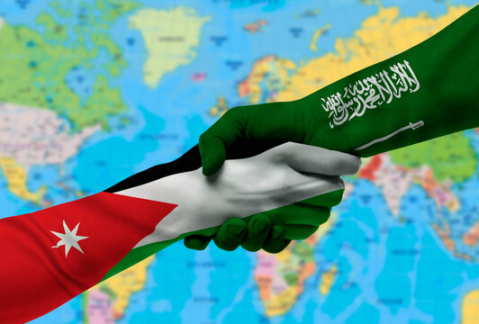 Handshake between Saudi Arabia and Jordan flags painted on hands.With background of world map - Powered by Adobe