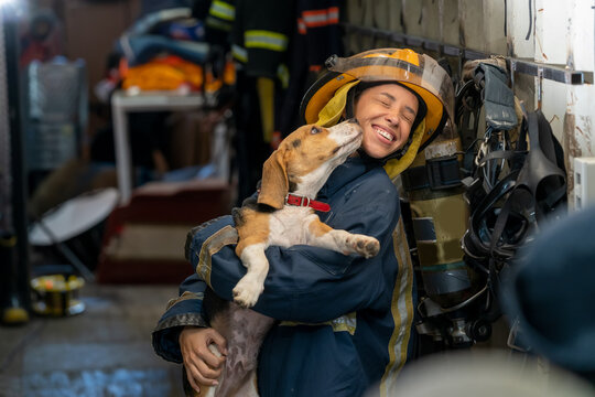 Portrait heroic fireman in protective suit holds saves dog in his arms,Firefighter in fire fighting operation.