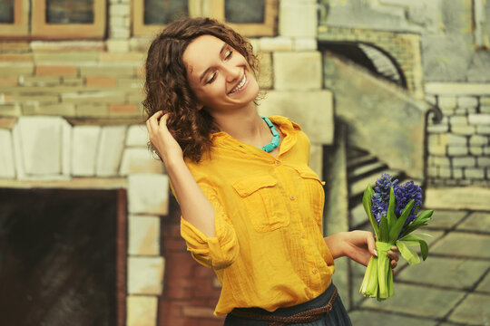 Happy young fashion woman in yellow shirt with bouquet of flowers