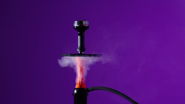 Smoking an orange hookah on a purple background with smoke. Black hookah on neon background, no people
