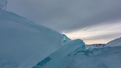 A block of ice hummocks on a frozen lake. Close-up. The glare of the sun on the edges of turquoise...