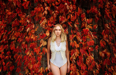 A beautiful young woman is seen leaning on the 
wall of an old house.She is surrounded by vines...