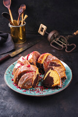 Traditional exotically bundt marble cocoa chocolate cake with icing sugar glaze and freeze dry raspberry topping served as close-up on a Nordic design plate