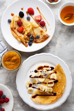 Two Crepes With Banana Slice, Berries Jam And Chocolate Sauce Food Overhead View