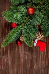 The concept of a Christmas background. Top view of red balls with fir branches on a wooden background.