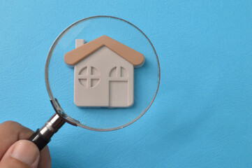Toy house with magnifying glass. House search, buying and selling real estate concept