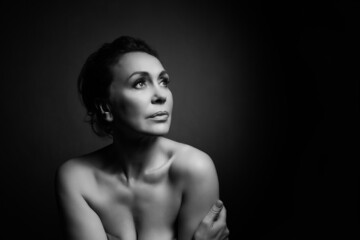 Portrait of a sensual fifty year old woman on grey studio background. Monochrome shot.