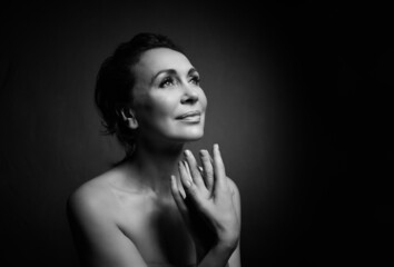 Fototapeta premium Portrait of a sensual fifty year old woman on grey studio background. Monochrome shot.