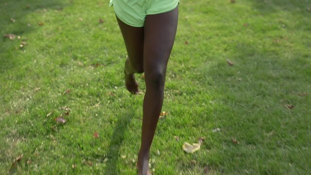 African american woman running on grass with barefoot