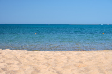 Seascape with surface of blue sea water with small ripple waves crashing on yellow sandy beach. Travel and vacations concept