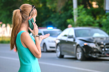 Stressed woman driver talking on mobile phone on street side calling for emergency service after car accident. Road safety and insurance concept