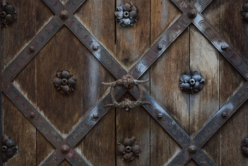 Close-up and detailed view and background of an old historical door, which is decorated with iron...